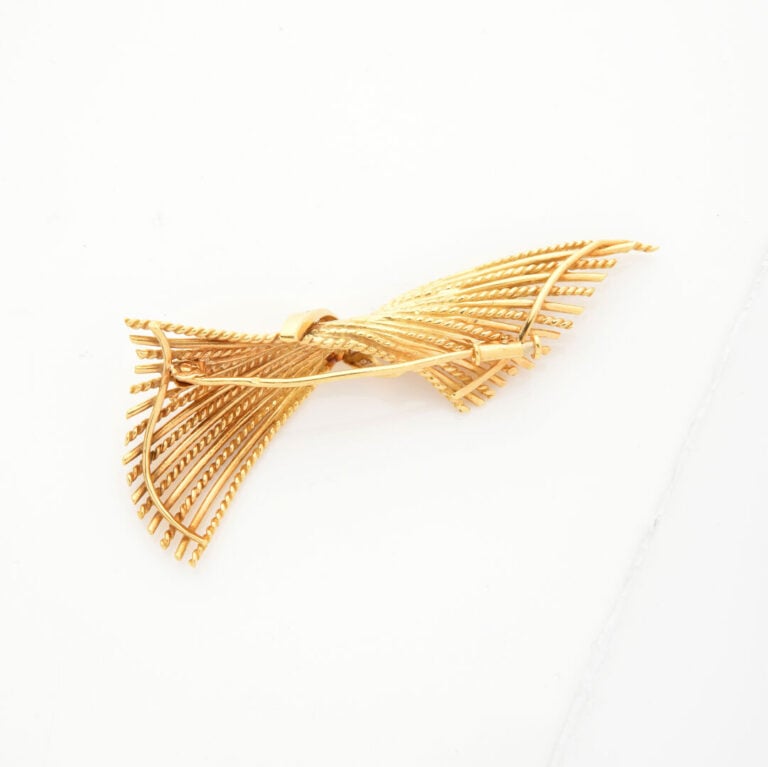 BROCHE « noeud » or jaune (750‰) partiellement torsadé, souligné de diamants ta…