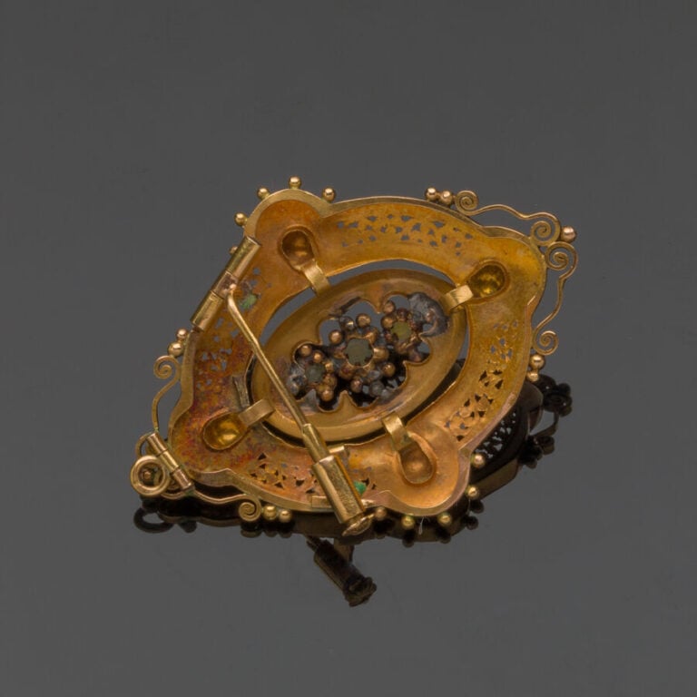 BROCHE ovale en or jaune (750‰) ajouré et ciselé, à motifs de volutes, orné de…