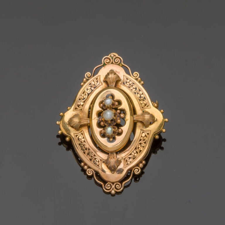 BROCHE ovale en or jaune (750‰) ajouré et ciselé, à motifs de volutes, orné de…