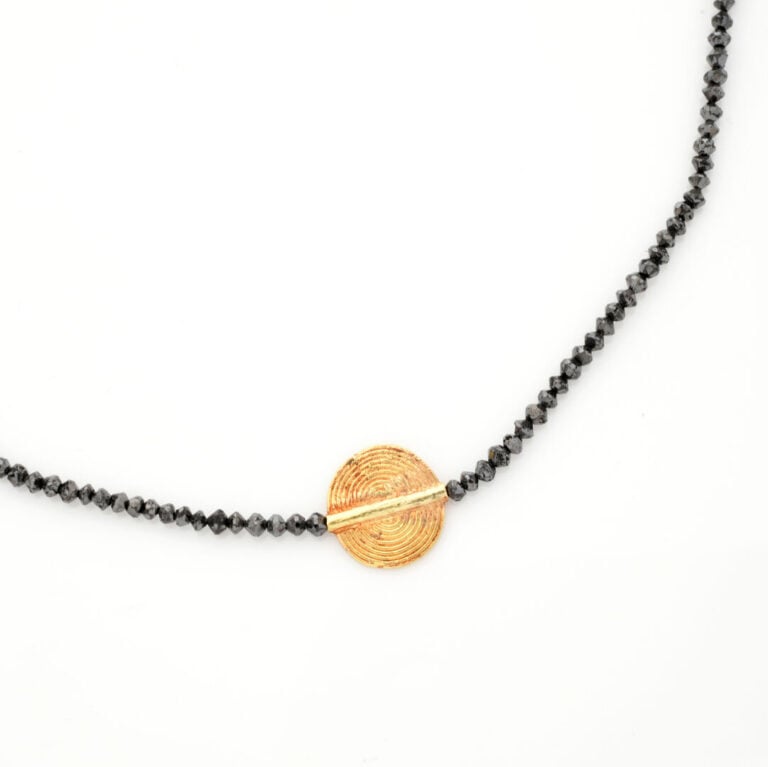 COLLIER composé d'un rang de perles facettées et diamants noirs, centré d'un mo…