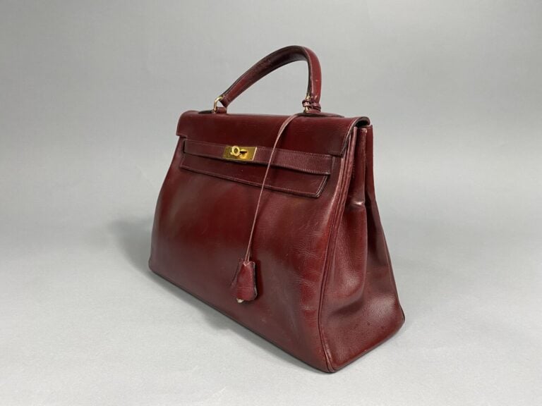 HERMÈS - Année 1959. - Sac Kelly 32 cm en box bordeaux, bijouterie dorée. - Cle…