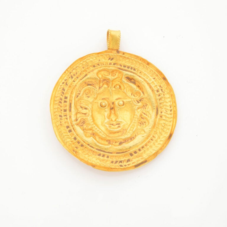 Important PENDENTIF circulaire en or jaune (750‰) repoussé, figurant la tête de…