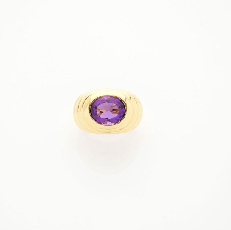 Importante BAGUE en or jaune (750‰) godronné, surmonté d'une améthyste ovale. -…