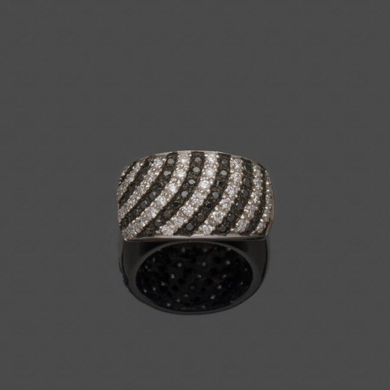 Large BAGUE légèrement bombée en or gris et or noirci (750‰) serti de seize ali…