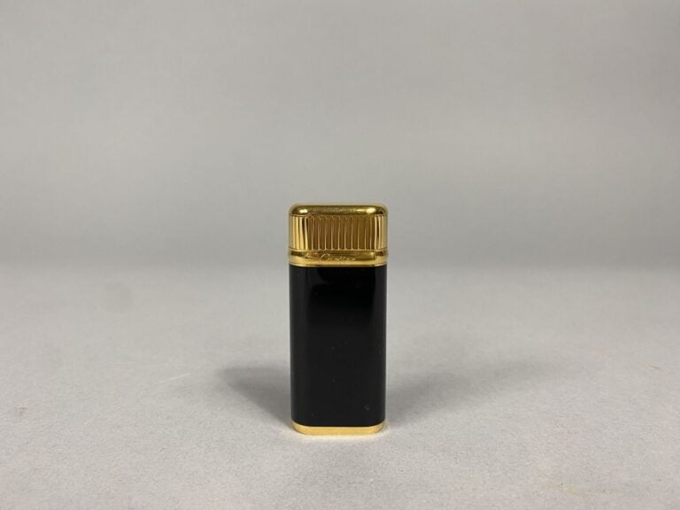 Must de CARTIER - Briquet en métal doré laqué noir - Signé et numéroté - Avec é…