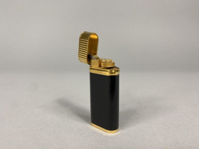 Must de CARTIER - Briquet en métal doré laqué noir - Signé et numéroté - Avec é…