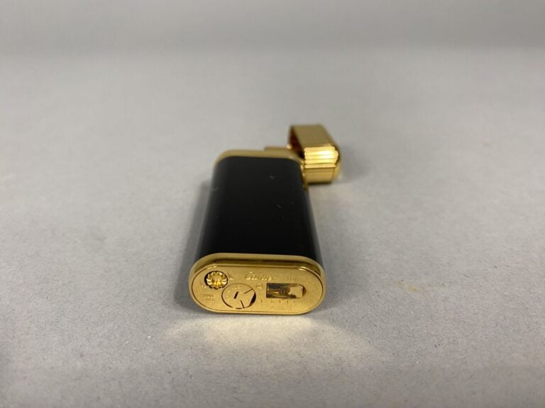 Must de CARTIER - Briquet en métal doré laqué noir - Signé et numéroté - Avec é…