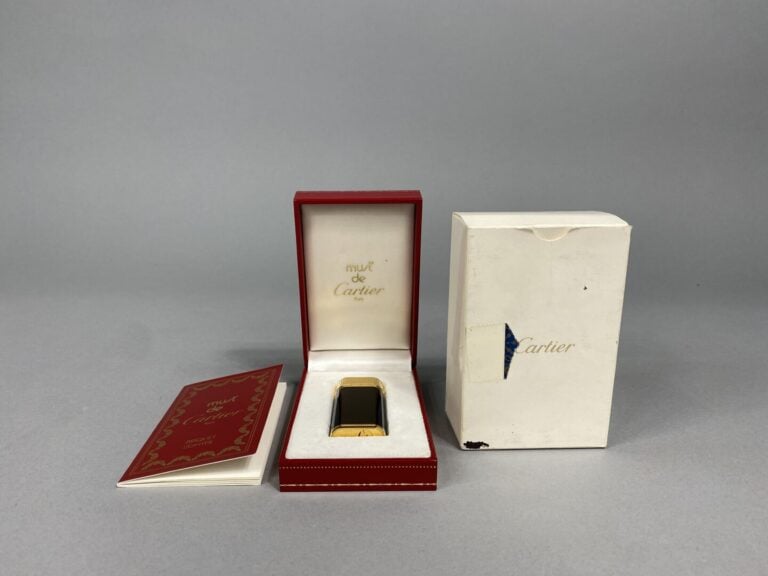 Must de CARTIER - Briquet en métal doré laqué noir - Signé et numéroté - Avec é…