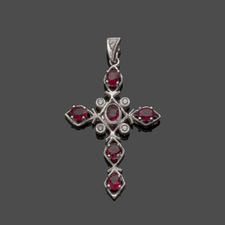 PENDENTIF "croix" en or gris (750‰) ajouré et ciselé, serti de rubis ovales et…