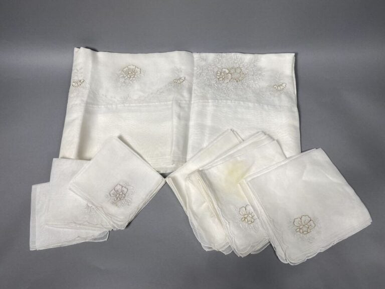 Nappe en organdi blanc à décor brodé de motifs floraux rehaussé de lurex. - On…