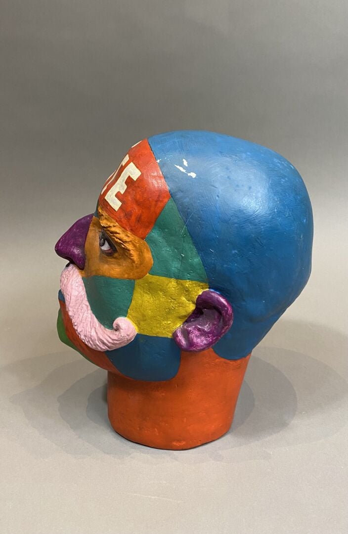 Sculpture en platre figurant une tête d'homme polychrome avec une inscription "…