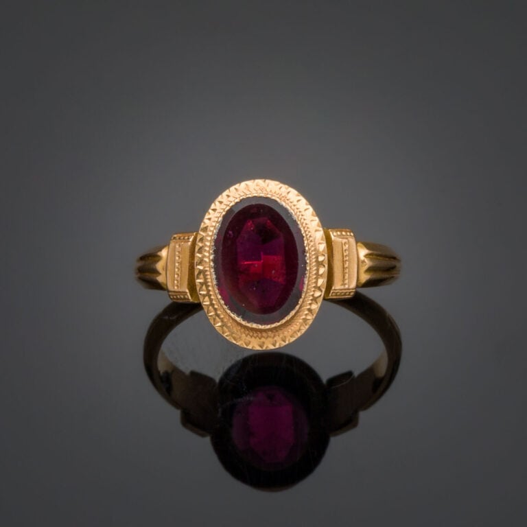 BAGUE en or rose (750‰) ciselé, serti d'un grenat ovale. - Travail français. -…