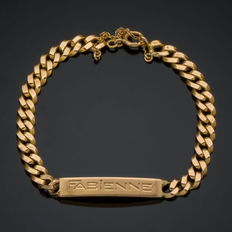 BRACELET gourmette en or jaune (750‰) retenant une plaque gravée "Fabienne" et…