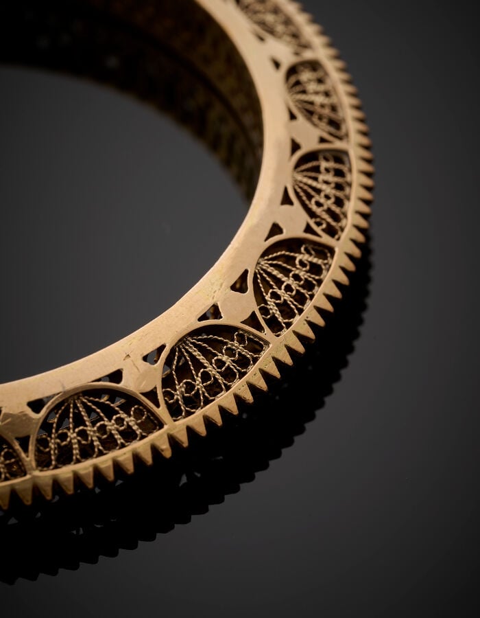 BRACELET rigide en or jaune (750‰) ciselé, cranté et filigrané. - Long.: 17 cm…
