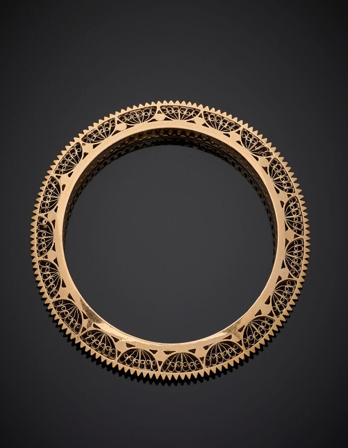 BRACELET rigide en or jaune (750‰) ciselé, cranté et filigrané. - Long.: 17 cm…