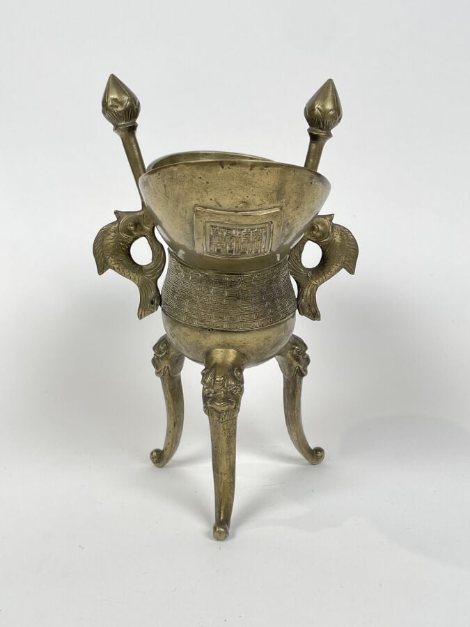 CHINE - COUPE LIBATOIRE tripode en bronze doré ; les pieds agrémentés de têtes…