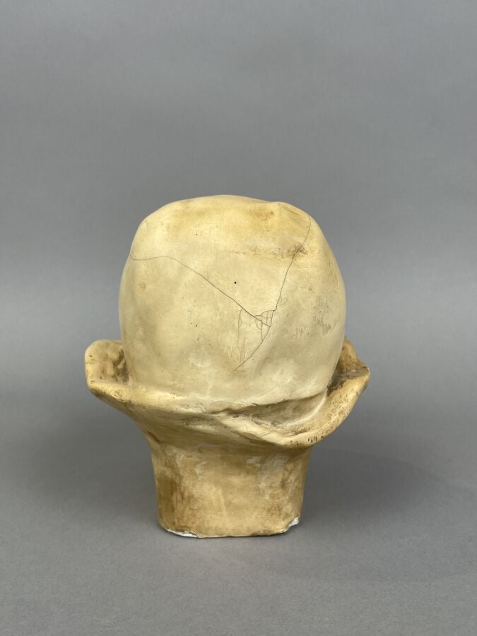 TETE DE BEBE en plâtre patiné (fentes, manques) - Hauteur : 16 cm - Provient de…
