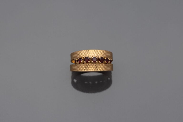 Bague en or jaune (750) à décor guilloché ornée d'une ligne de pierres rouges f…