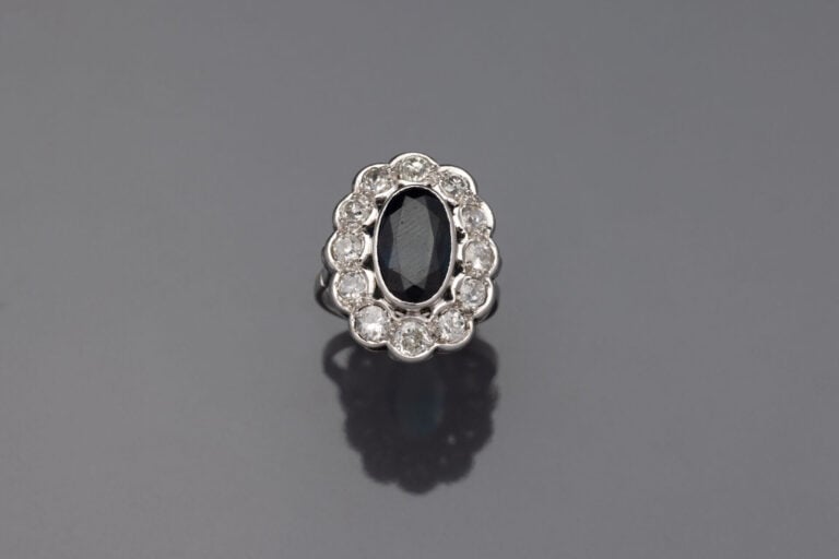 BAGUE "marguerite" en or gris (750‰) et platine (950‰) ornée d'un saphir foncé…
