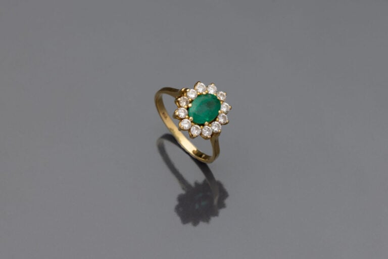 BAGUE "marguerite" en or jaune (750) serti d'une émeraude de forme ovale dans u…