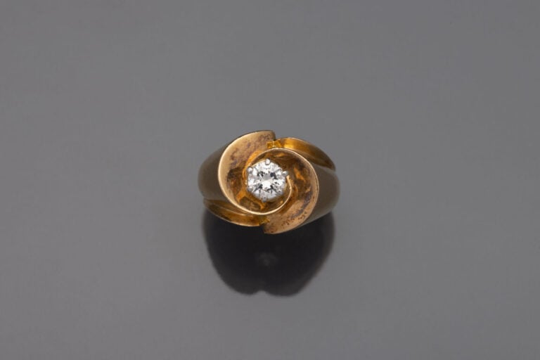 BAGUE " tourbillon " en or jaune (750) centrée d'un diamant taille brillant. -…