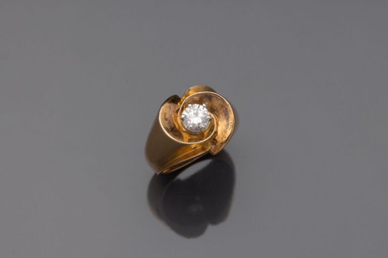 BAGUE " tourbillon " en or jaune (750) centrée d'un diamant taille brillant. -…