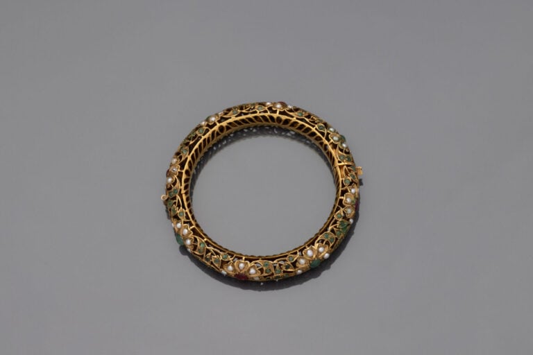 Bracelet rigide ouvrant tubulaire en métal doré serti de demi-perles et pierres…