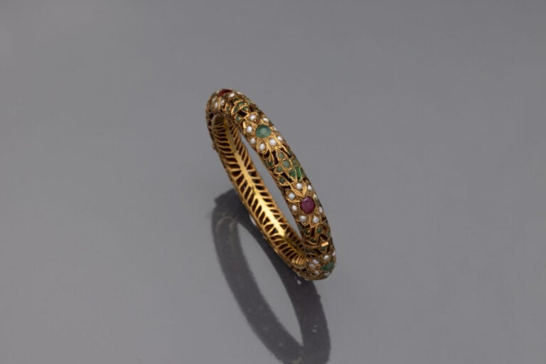 Bracelet rigide ouvrant tubulaire en métal doré serti de demi-perles et pierres…