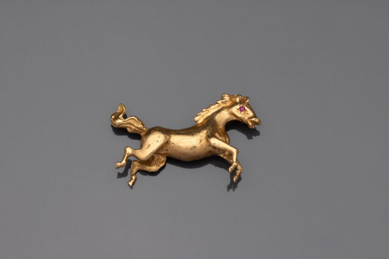 Broche en or jaune (750) à décor guilloché figurant un cheval au galop, l'oeil…