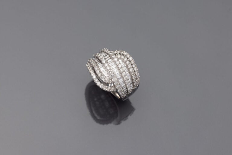 Importante BAGUE "volutes" en or gris (750‰) ajouré, serti de six alignements d…