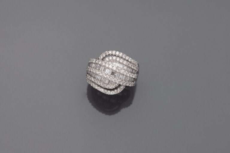 Importante BAGUE "volutes" en or gris (750‰) ajouré, serti de six alignements d…