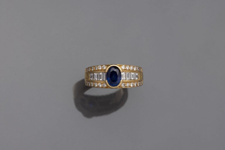 KORLOFF - BAGUE " bandeau " en or jaune (750‰) serti d'un saphir ovale épaulé d…