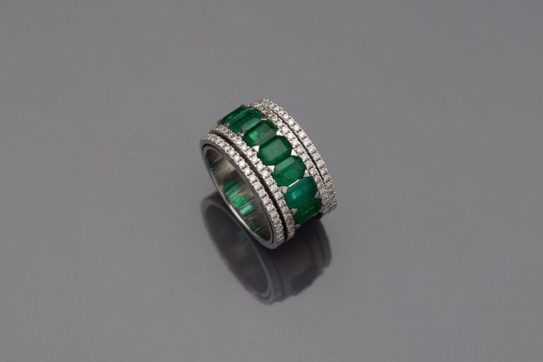 Large BAGUE en or gris (750‰) serti d'un alignement de sept émeraudes taillées…