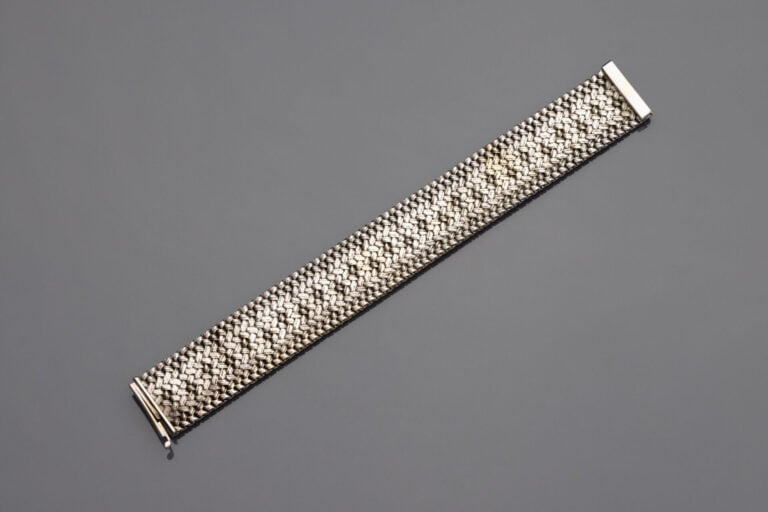 Large BRACELET ruban en or gris (750) partiellement amati. - Vers 1970. Dans so…