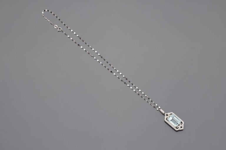 PENDENTIF et sa chaînette, en or gris (750‰) ajouré à motifs de volutes serti d…