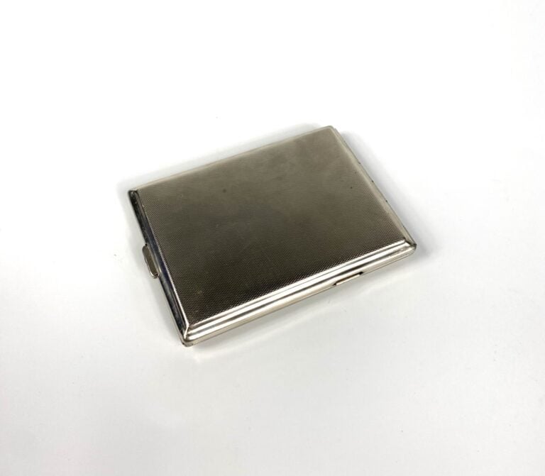 Etui à cigarettes en métal argenté à motif de volutes. - 11 x 8 cm. - Bon état…