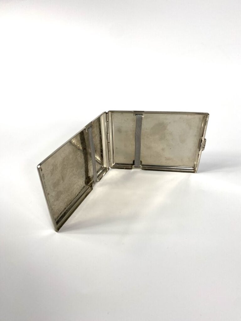 Etui à cigarettes en métal argenté à motif de volutes. - 11 x 8 cm. - Bon état…