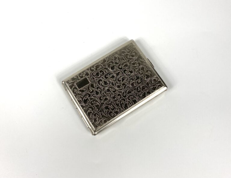 Etui à cigarettes en métal argenté à motif de volutes. - 11 x 8 cm. - Bon état…