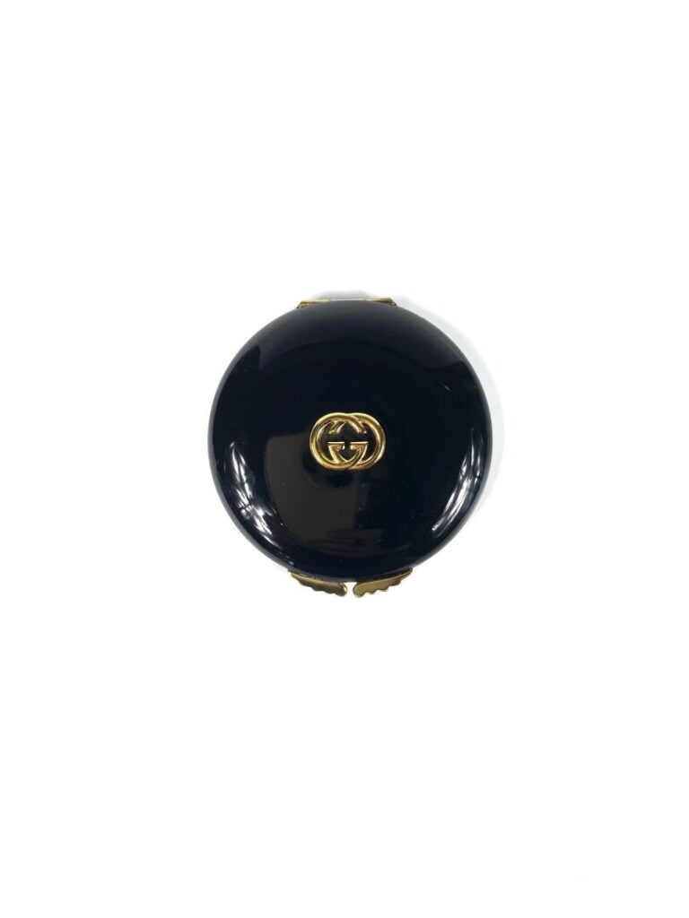 GUCCI - Poudrier siglé en métal doré émaillé noir, miroir (signé) - Diam. 8 cm…