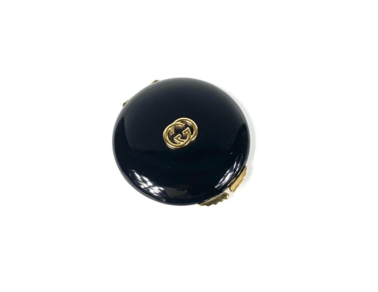 GUCCI - Poudrier siglé en métal doré émaillé noir, miroir (signé) - Diam. 8 cm…