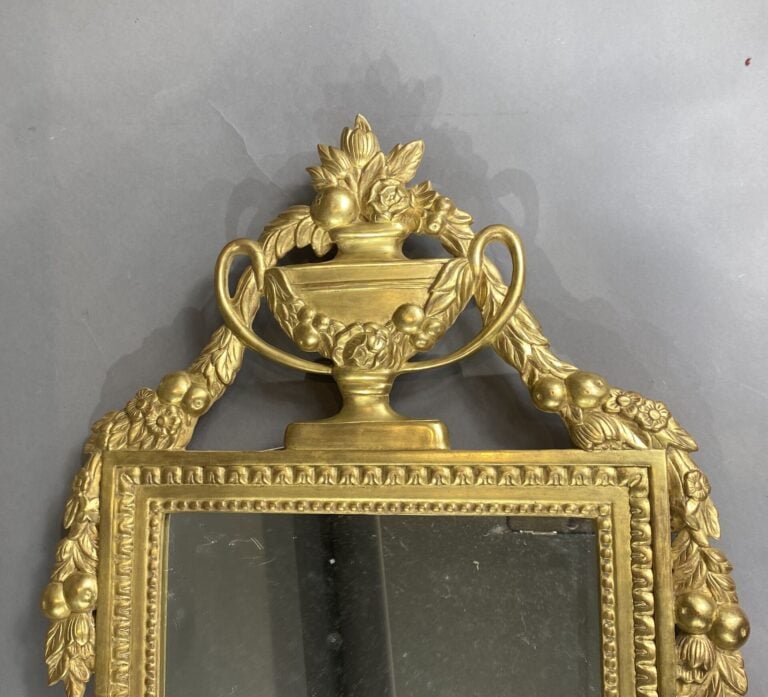 Miroir en bois doré à fronton à décor de vase fleuri et guirlandes, frise de pe…