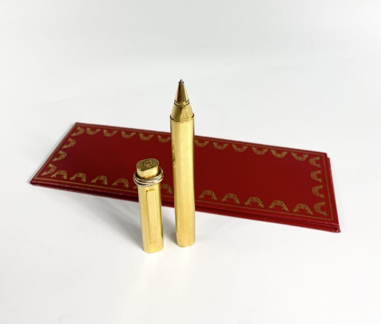 MUST DE CARTIER - Stylo bille "Trinity" en métal plaqué or strié, numéroté. - L…
