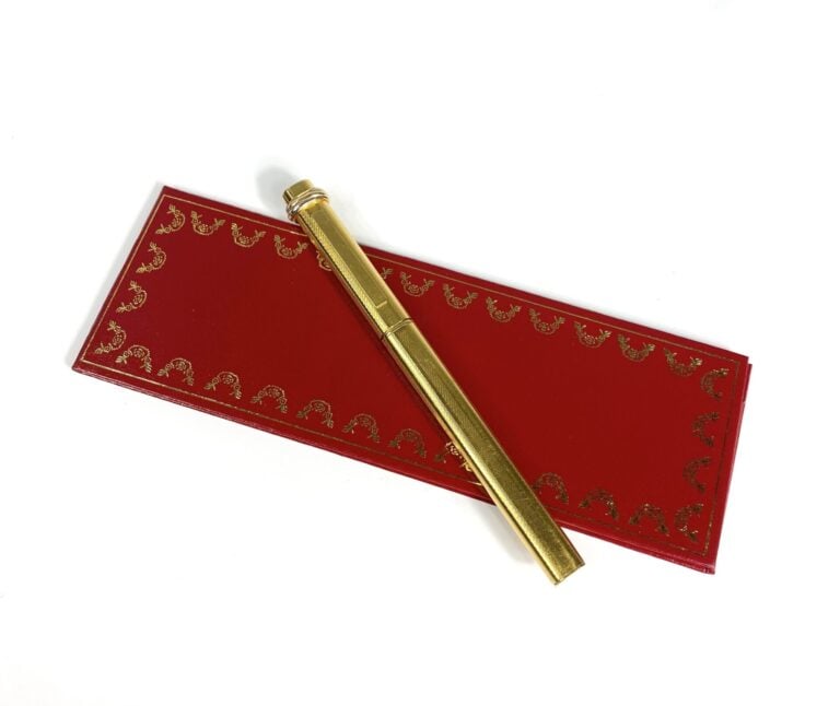 MUST DE CARTIER - Stylo bille "Trinity" en métal plaqué or strié, numéroté. - L…