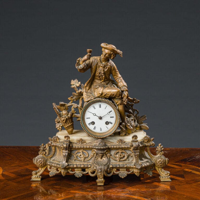Pendule en régule doré représentant un homme tenant une coupe sur un tertre à d…