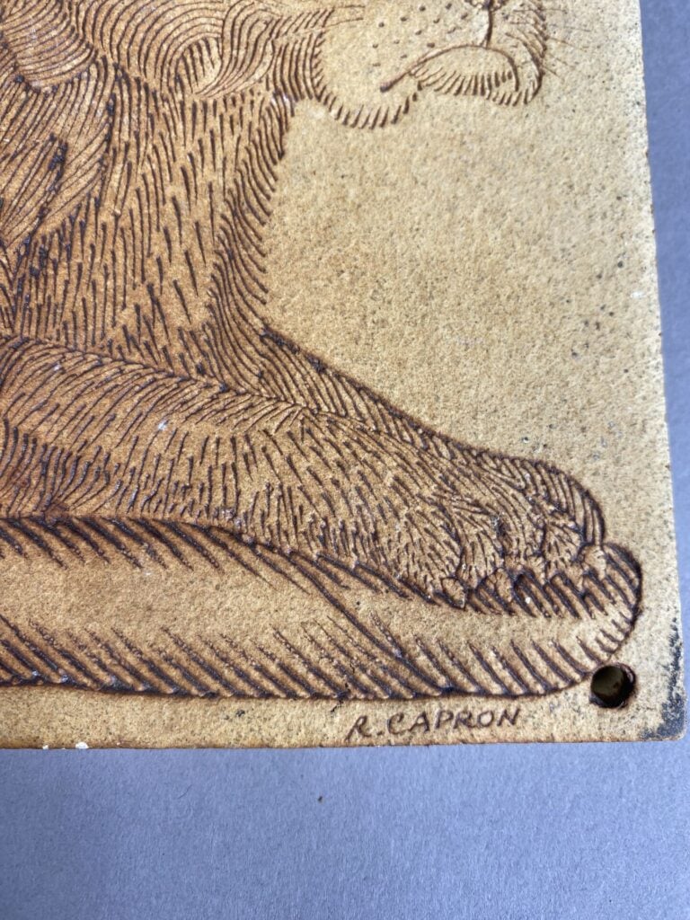 Plaque en faïence à décor gravé d'un chien couché - Porte une signature R. CAPR…