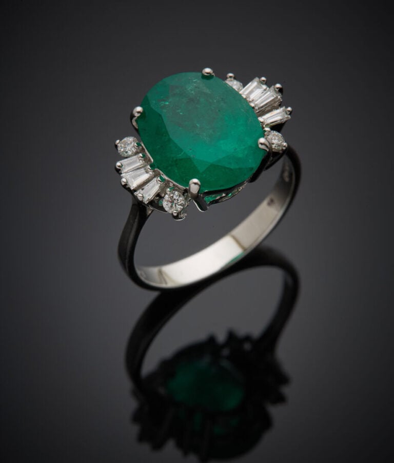 BAGUE en or gris (750‰) serti d'une émeraude de forme ovale, épaulé de diamants…