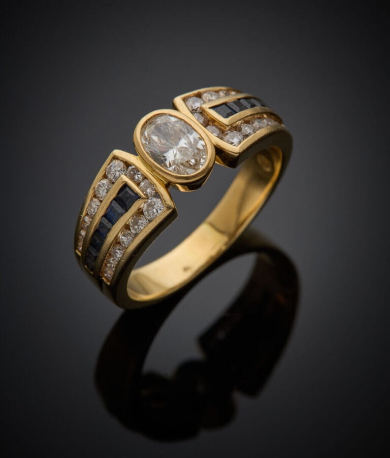 BAGUE en or jaune (750‰) centrée d'un diamant ovale en serti clos, épaulé d'ali…