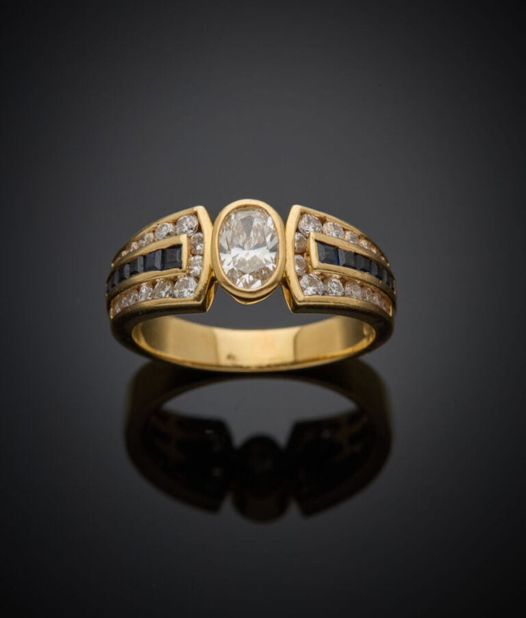 BAGUE en or jaune (750‰) centrée d'un diamant ovale en serti clos, épaulé d'ali…