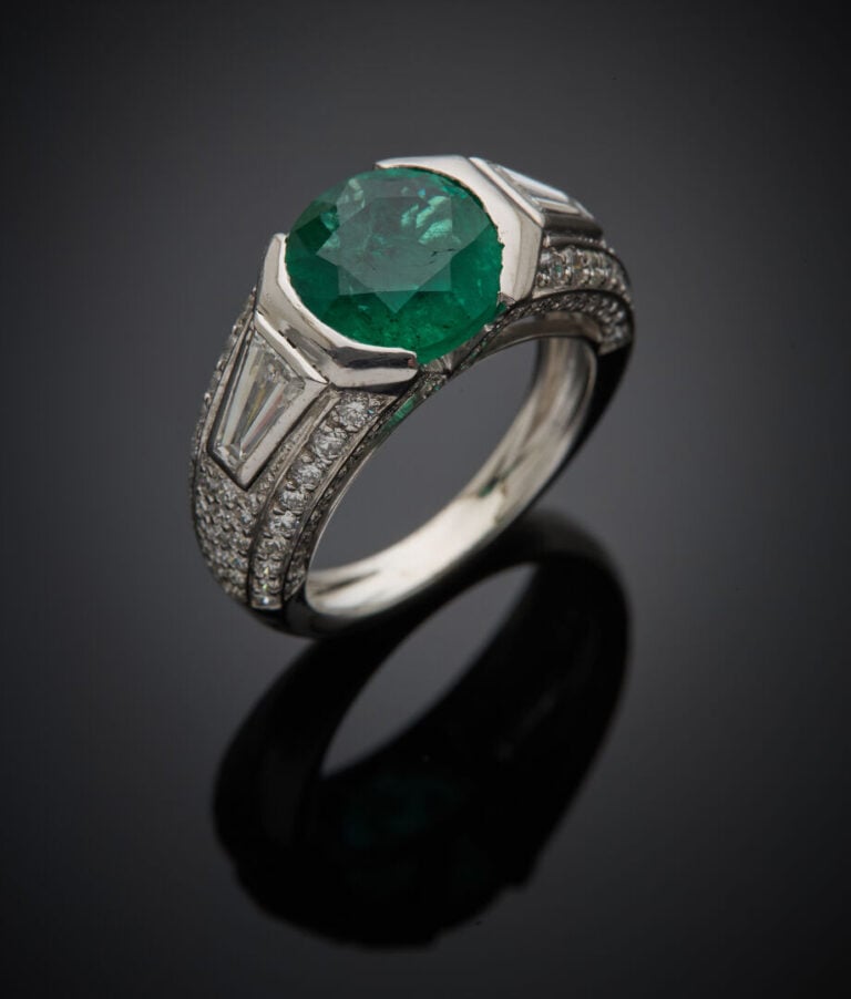 BAGUE "jonc" en or gris (750‰) ajouré surmontée d'une émeraude ronde épaulée de…