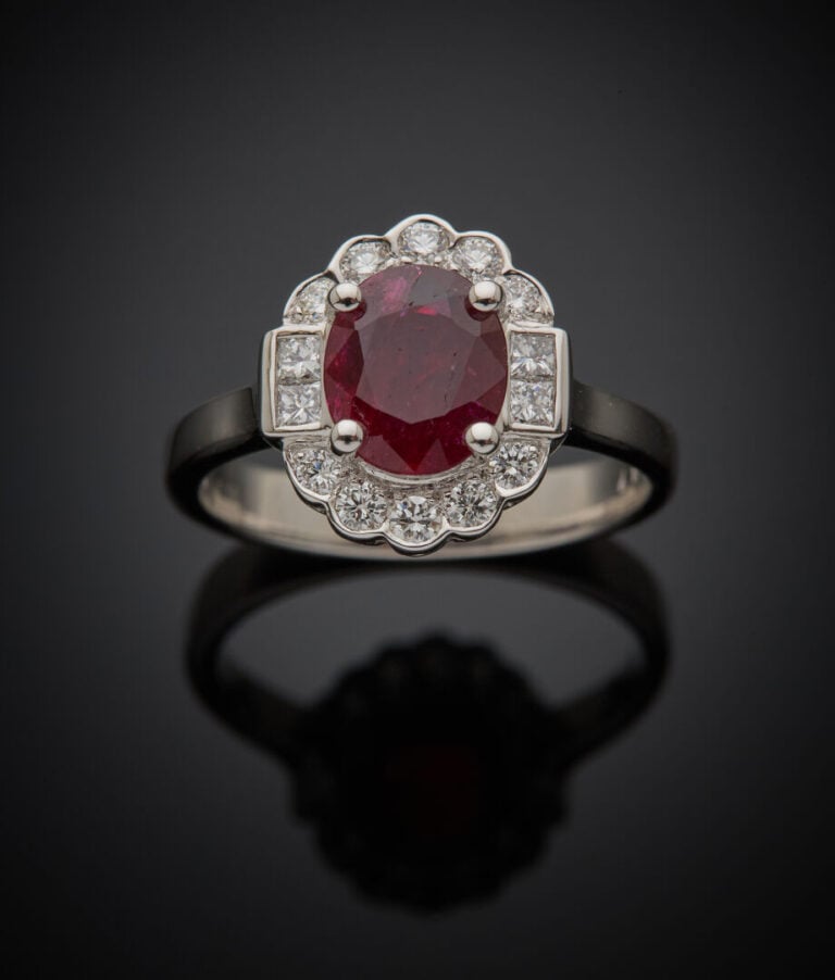 BAGUE "marguerite" en or gris (750‰) serti d'un rubis ovale pesant 1,14 carat,…